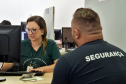 Usuário de costas utilizando uma camiseta com a palavra "segurança" é atendido por uma servidora da Defensoria no Mutirão realizado em Maringá. 