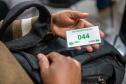 Detalhe mostra senha de atendimento na mão de assistido da DPE-PR. 