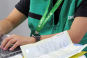 Imagem mostra detalhe de servidora com colete da DPE-PR. 