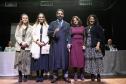 Novo defensor público empossado posa de beca com a carteira funcional ao lado de familiares e das primeira e segunda subdefensora pública geral.   