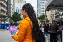 Mulher de costas segura os panfletos com informações sobre violência de gênero e onde procurar apoio.  