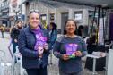 Mulheres seguram panfletos da Tenda Lilás.