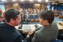 DPG Matheus Munhoz e presidente do TCE apertam as mãos, ao fundo a platéia. 