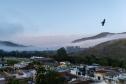 Imagem mostra vista aérea de Barra do Turvo, no Vale da Ribeira. No céu, um pássaro voa no canto esquerdo da imagem e a fundo montanhas cobertas por um mar de nuvens. 
