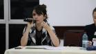 A imagem mostra a Dra. Flávia Palazzi, Diretora da EDEPAR, com um microfone próximo a sua boca sentada na ponta direita da mesa de palestrantes. 