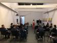 Na imagem vemos a equipe da DPPR palestrando aos guardas municipais. A equipe está de pé, ao fundo da sala, na frente dos oficias (esses estão sentados de costas).