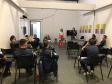 Na imagem vemos a equipe da DPPR palestrando aos guardas municipais. A equipe está de pé, ao fundo da sala, na frente dos oficias (esses estão sentados de costas).