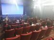 Na imagem vemos o encerramento do projeto no auditório da UNICENTRO. Temos os alunos sentados nas poltronas e as professoras em frente ao palco e telão. 