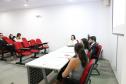 Na imagem vemos três pessoas sentadas de costas em uma mesa passando instruções aos novos defensores. 