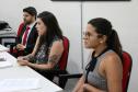 Na imagem vemos três pessoas sentadas a uma mesa principal passando informações aos novos defensores. 