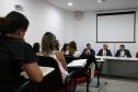 Na imagem vemos uma parte dos novos defensores sentados prestando atenção nos componentes da mesa a sua frente. 