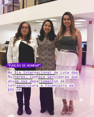 Imagem que mostra as três servidoras entrevistadas em pé, dentro da sede administrativa da Defensoria. As três estão em pé, uma ao lado da outra, abraçadas. Elas aolham para a fotos e sorriem. Ao fundo, é possível ver algumas mesas e computadores e o andar superior.