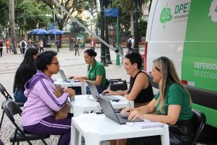 Imagem com foto de atendimento da DPE-PR com a Van dos Direitos.