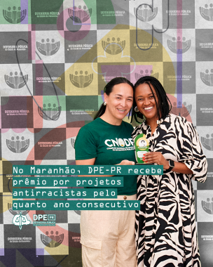 Foto da ouvidora-geral externa, Karollyne, e a vice-coordenadora do NUPIER, Elisabeth, segurando o prêmio. Elas sorriem para a foto. Karollyne é uma mulher trans negra de pele clara. Ela tem cabelos lisos, que estão amarrados para trás. A Elisabeth é uma mulher negra de pele retinta, com tranças no cabelo. Por cima da imagem, está o título da matéria e a logo da Defensoria. 
