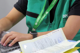 Imagem mostra detalhe de servidora com colete da DPE-PR. 