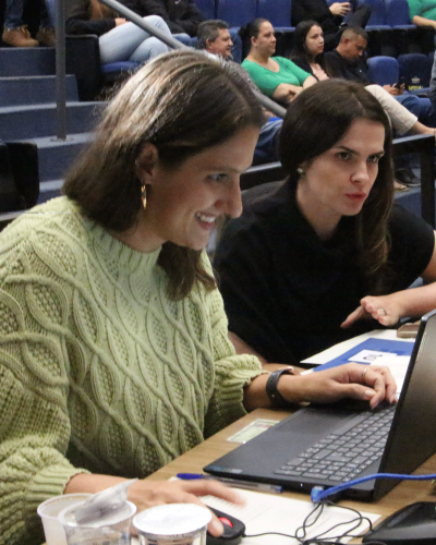 Imagem de uma defensoria sorrindo enquanto mexe no notebook.