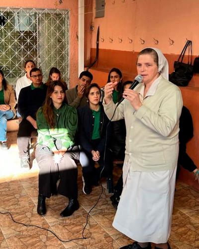 Imagem de uma representante de movimento social voltado para pessoas em situação de rua discursando no microfone. Defensores(as) sentado ao fundo prestando atenção.