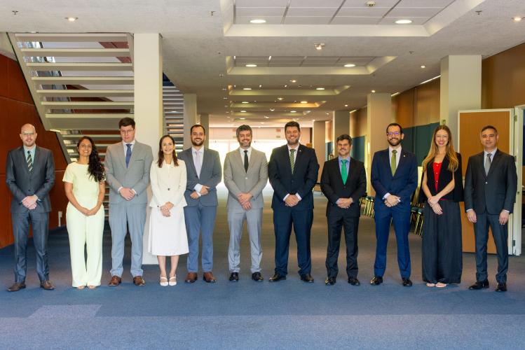 Imagem dos avaliadores da prova. Eles estão todos enfileirados com as mãos cruzadas na frente do corpo. Todos usam roupas formais.