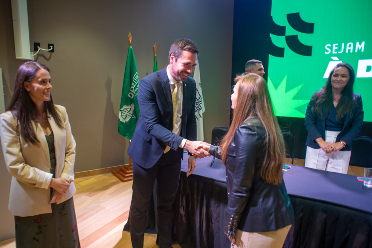 Imagem com foto em que o defensor público-geral do Paraná cumprimenta uma nova servidora empossa, ao lado de outros membros da administração superior.