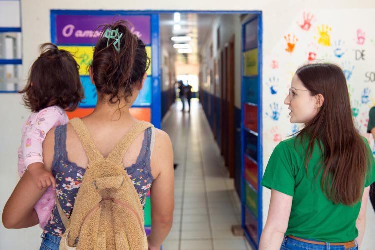 Mãe chega com a filha no colo para atendimento de Pensão Alimentícia em mutirão realizado pela DPE-PR em Pato Branco. Ao lado dela a Defensora Pública explica seus direitos.