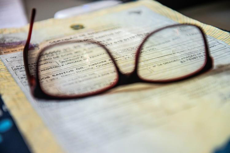 Imagem mostra uma imagem de um óculos sobre um documento desfocado.