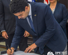 Foto mostra o Defensor Público-Geral André Giamberardino assinando o Termo de Cooperaão que retoma o projeto de atendimento a vítimas