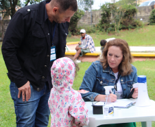 Imagem de uma servidora pública prestando orientação a um homem com sua filha.