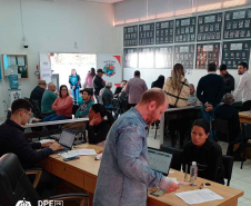 Imagem que mostra pessoas aguardando atendimento ou em atendimento na Câmara Municipal.