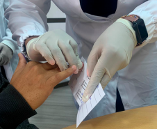 Imagem que mostra uma coleta de sangue da mão de um homem para a realização de exame de DNA.