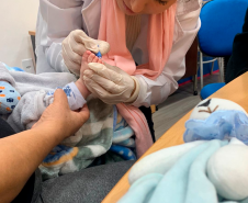 Imagem que mostra uma coleta de sangue do pé de um bebê para a realização de exame de DNA.