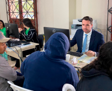 Imagem que mostra o Coordenador da Assessoria de Projetos Especiais, Matheus Cavalcanti Munhoz, atendendo o público junto aos defensores.