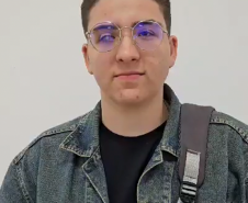 Imagem que mostra o entrevistado Diego Sikorski. Ele usa óculos, jaqueta jeans e carrega uma mochila.