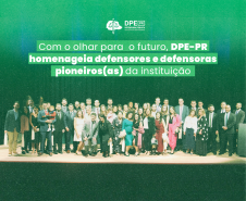 Imagem que mostra todos os defensores e defensoras presentes na cerimônia no palco do auditório. Acima da imagem está escrito o título da matéria.