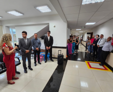 Imagem que mostra a inauguração da sala da DPE-PR em Cruzeiro do Oeste. Várias pessoas estão em pé, em um corredor e em uma pequena sala de recepção do Fórum, assistindo a solenidade.