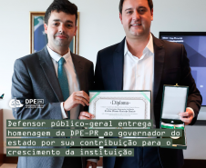 Imagem com a foto do Defensor Público-Geral, André Giamberardino, entregando ao governador do estado do Paraná, Carlos Massa Ratinho Junior, um certificado e uma medalha de homenagem pela colaboração com o crescimento da Defensoria.  Os dois são homens caucasianos altos e com cabelos castanhos. Ambos usam terno e gravata. Alinhado à esquerda, o título da matéria, tarjado em verde e, acima, o logo da Defensoria em branco.