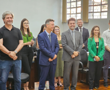 Imagem que mostra representantes da Defensoria e autoridades convidadas na inauguração da sala da DPE-PR em Jandaia. As pessoas, 4 mulheres e 5 homens, estão em pé, diante de cadeiras e todos riem.