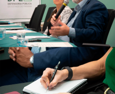 Imagem com duas fotos: acima, o desembargador Marcelo Semer e a defensora pública Gabriela Schirmer; abaixo, detalhe de participante da palestra escrevendo em caderno.