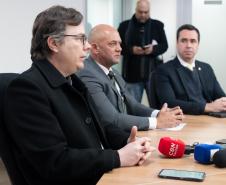 Imagem com o diretor-geral da Polícia Científica, Luiz Rodrigo Grochocki, juntamento do secretário de Segurança Pública, Hudson Leôncio Teixeira,  e do Defensor Público-Geral, Matheus Munhoz, sentados em uma mesa e se pronunciando durante a coletiva de imprensa