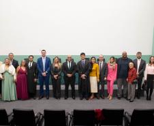 Imagem horizontal colorida em que se vê todos os presentes na cerimônia de posse dos Novos Defensores posando juntos no auditório. 