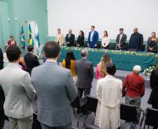 Imagem horizontal colorida onde se vê o público em primeiro plano e ao fundo a mesa de representantes da instituição que conduziram a cerimônia de posse dos novos Defensores Públicos do Paraná. 