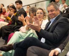 Imagem horizontal colorida em que se vê o público aplaudindo durante a cerimônia de posse dos novos Defensores Públicos. 