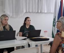 Imagem que mostra um dos atendimentos do evento. Duas pessoas da Defensoria atendem uma senhora. 