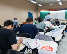 Imagem horizontal colorida que mostra os candidatos realizando as provas. 