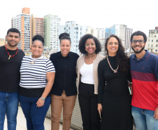 imagem com a equipe no NUPIER sorrindo na sacada da sede central de atendimento da Defensoria 