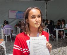 Imagem horizontal colorida em que aparece um assistido saindo com atendimento com documentos do processo iniciado junto a DPE-PR.