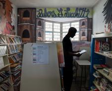Imagem horizontal colorida em que se vê jovem na biblioteca da unidade socioeducacional.  