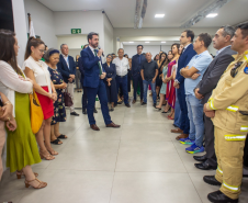 Defensor público realiza discurso em um púlpito dentro da nova sede, com banner institucional ao fundo. O público, composto por autoridades e convidados, acompanha atentamente.