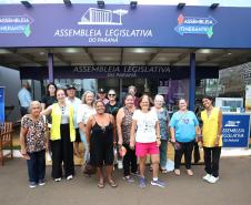 Imagem colorida horizontal em que se vê um grupo de pessoas posando em frente a entrada do evento Assembleia Itinerante, em Londrina.