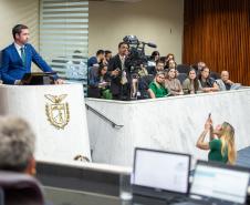 Em primeiro plano a mesa diretiva da ALEP-PR, ao fundo Defensor Público Geral discursa na Tribuna e representantes da instituição acompanham a sessão do primeiro balcão. 