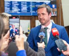 O Defensor Público Geral fala para a imprensa, cercado por microfones, câmaras e celulares.  